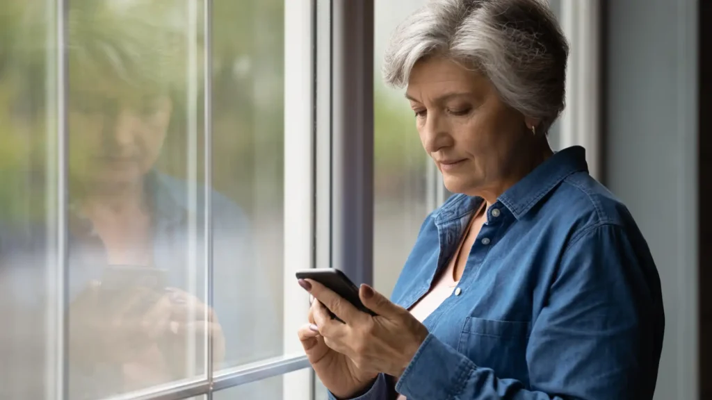 woman at the window holding a cell phone