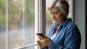 woman at the window holding a cell phone
