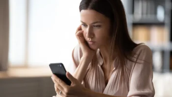 woman sitting worried looking at her cell phone