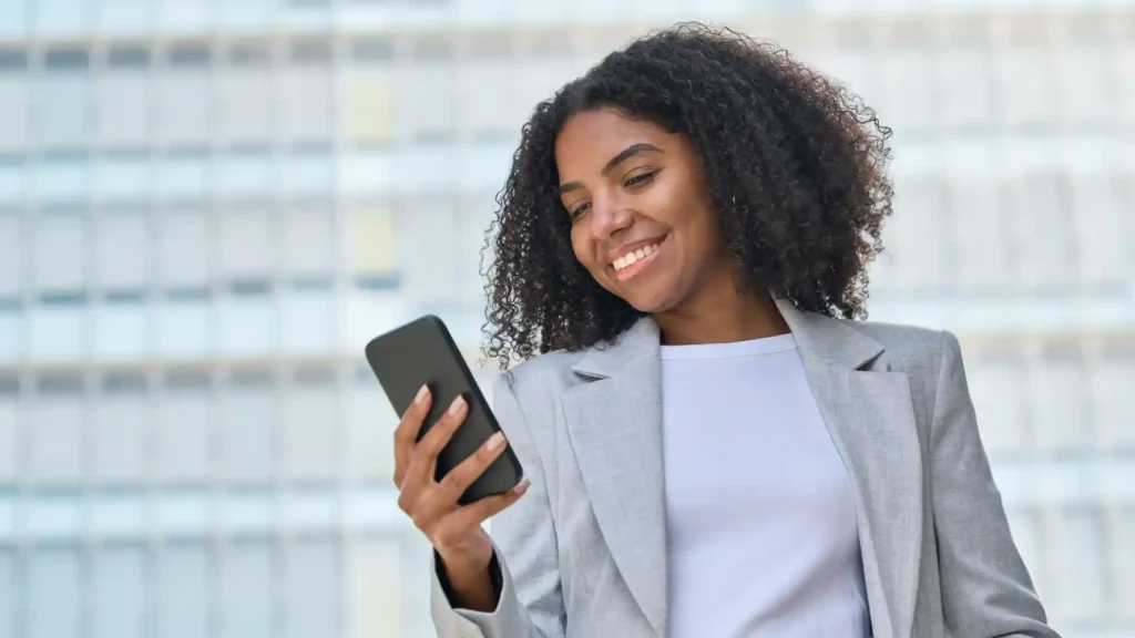 woman in business attire looking at a cell phone