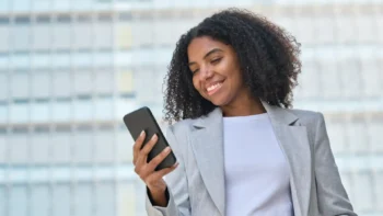 woman in business attire looking at a cell phone