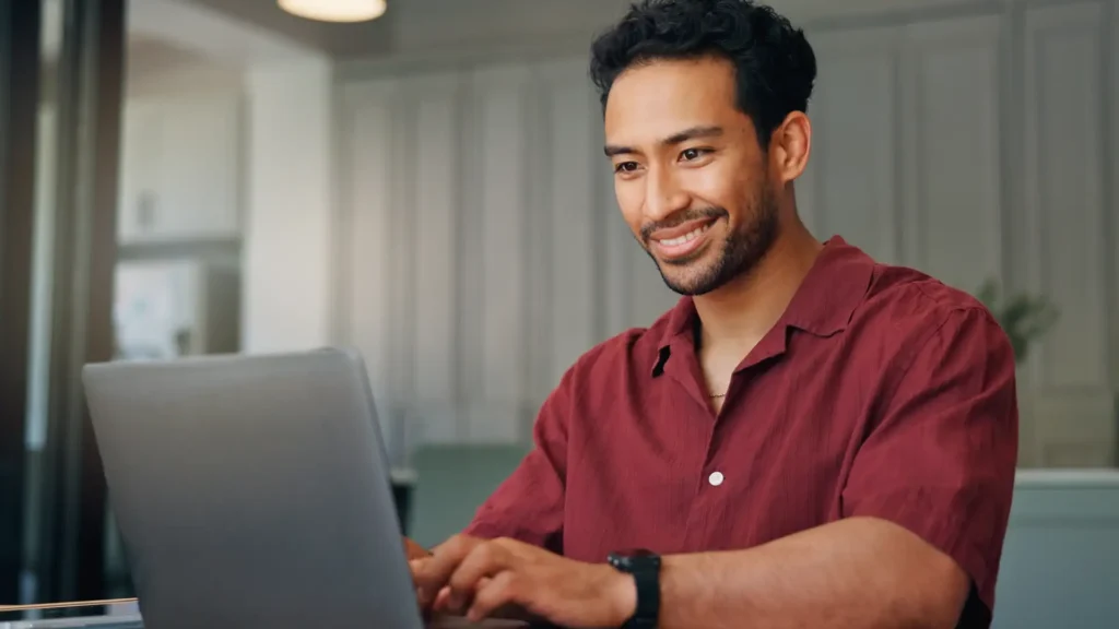 Man smiling typing on laptop