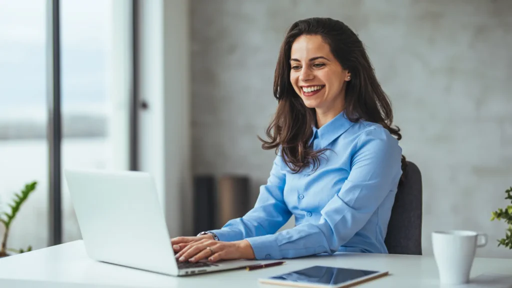 Woman at a desk with laptop smiling