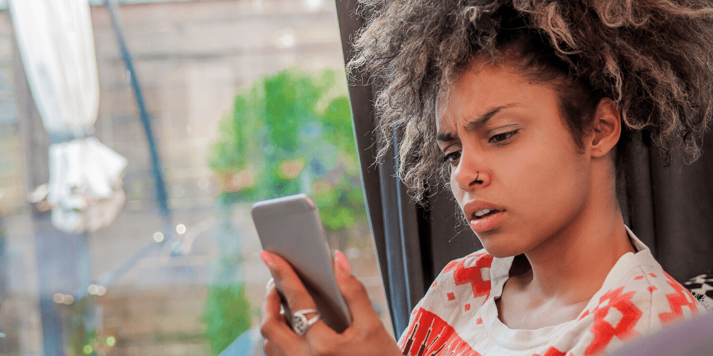 A woman looking at her phone with a confused expression