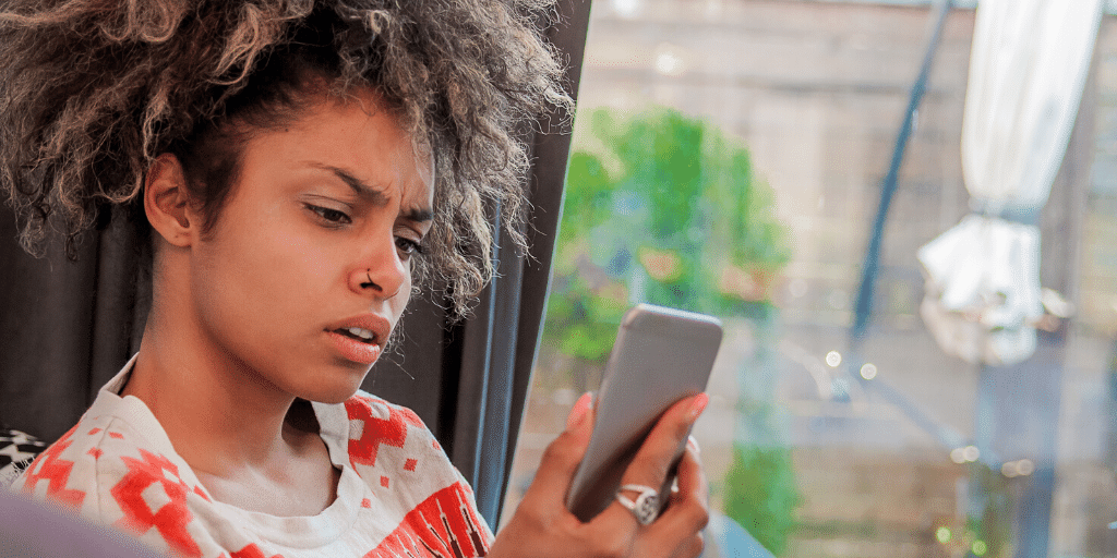 woman looking at her smartphone with a confused look