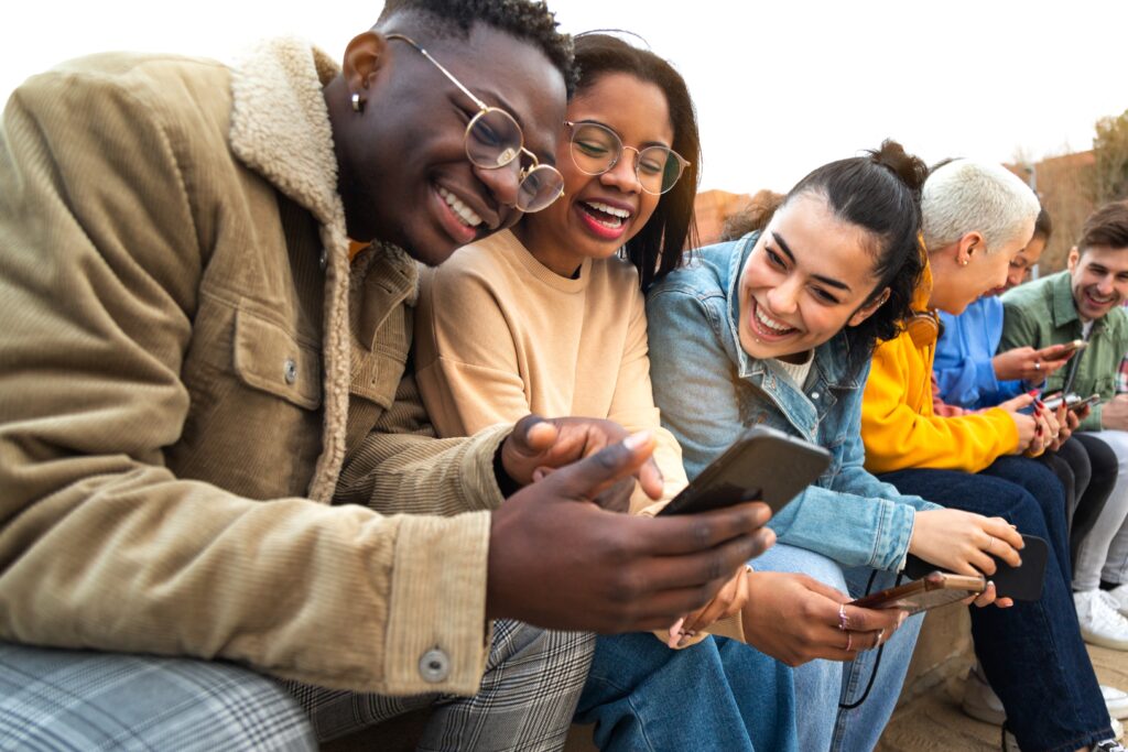 Group of happy students having fun while looking at a phone