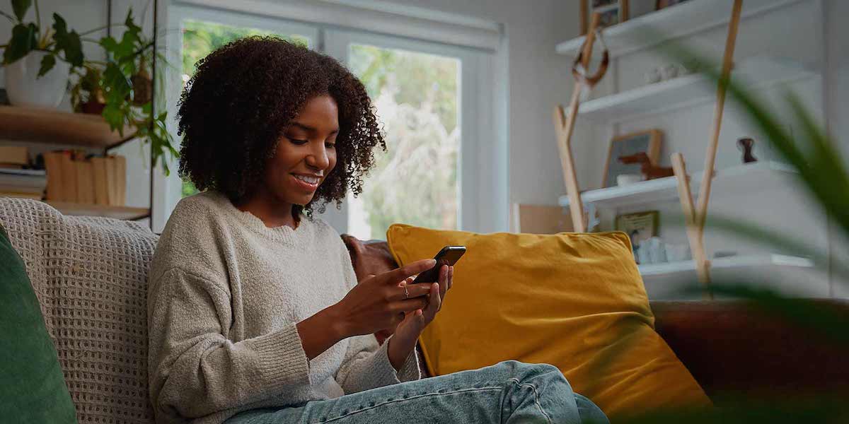 woman sitting on a couch using a mobile device