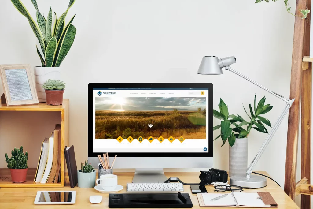 Computer placed over a wooden desk featuring plants and a gray lamp