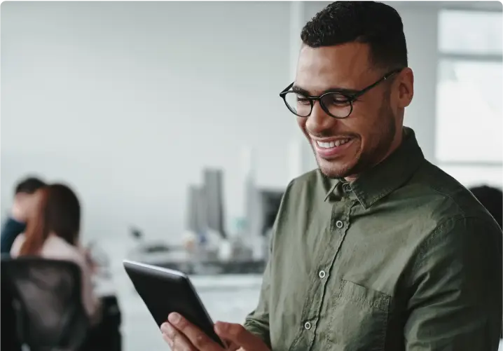 A man smiling while looking at tablet