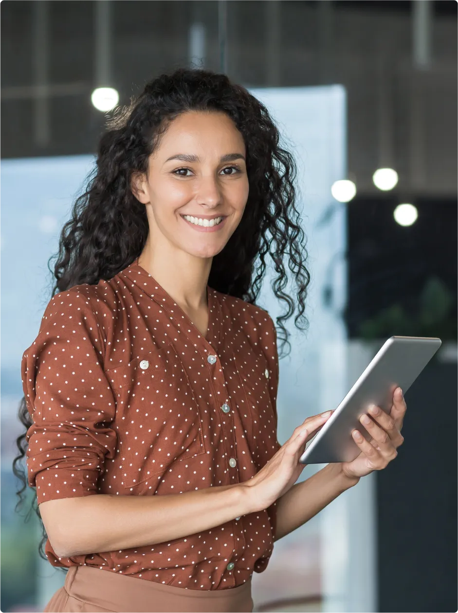 Woman smiling, holding a tablet in her hand