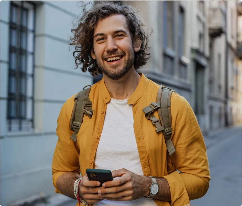 A happy man standing outside a building with his phone