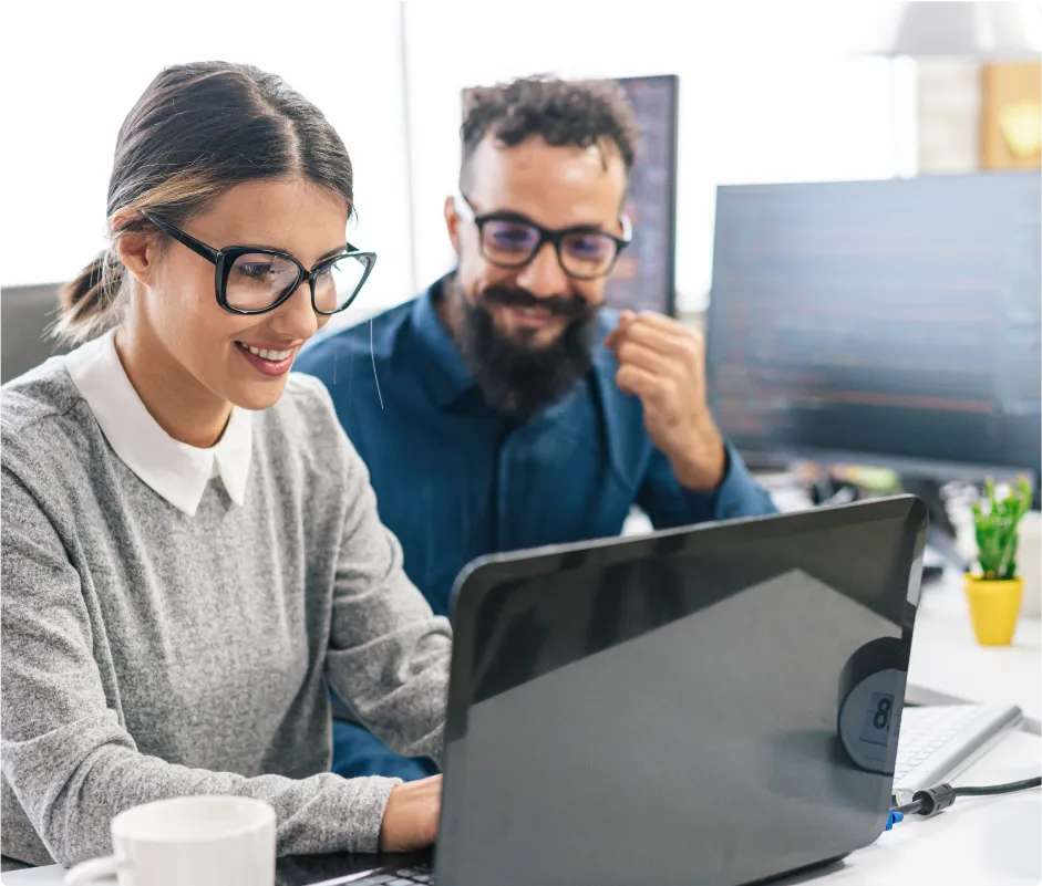 Man and woman in an office working on a laptop