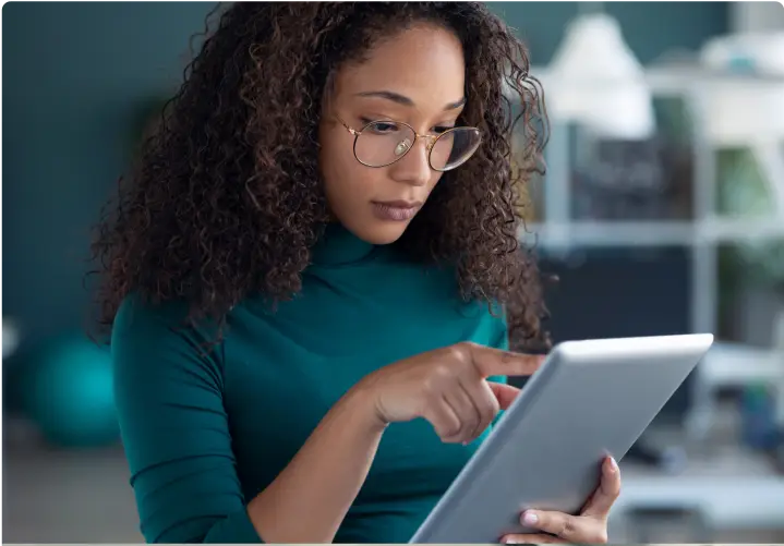 A woman wearing glasses working on her tablet