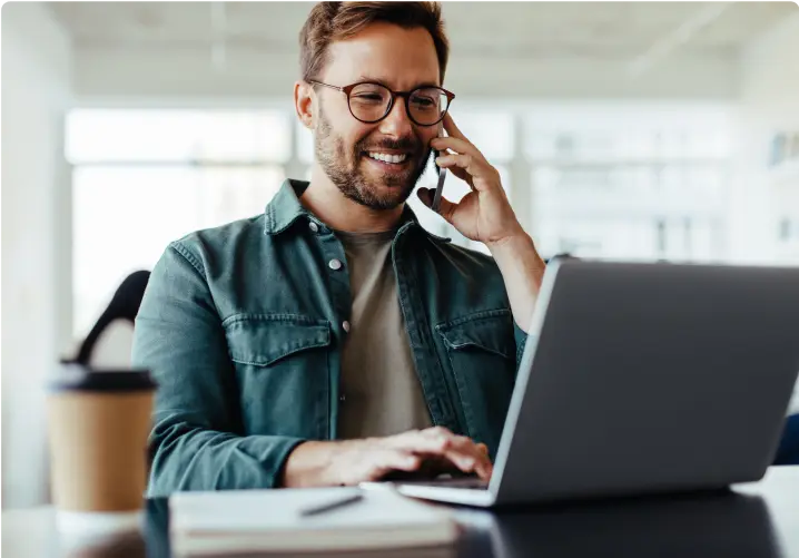 Man working on a laptop and talking on the phone