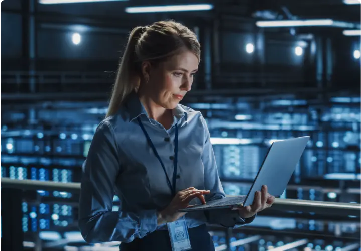 Woman in an office standing while holding an open laptop