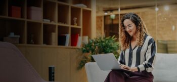 Woman seated on a couch, working on a laptop