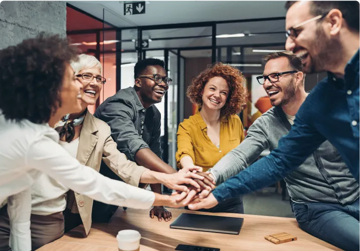 Group of people in a office room putting their hands together