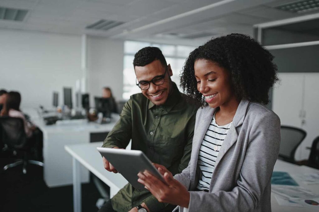 Man and woman smiling and using a tablet