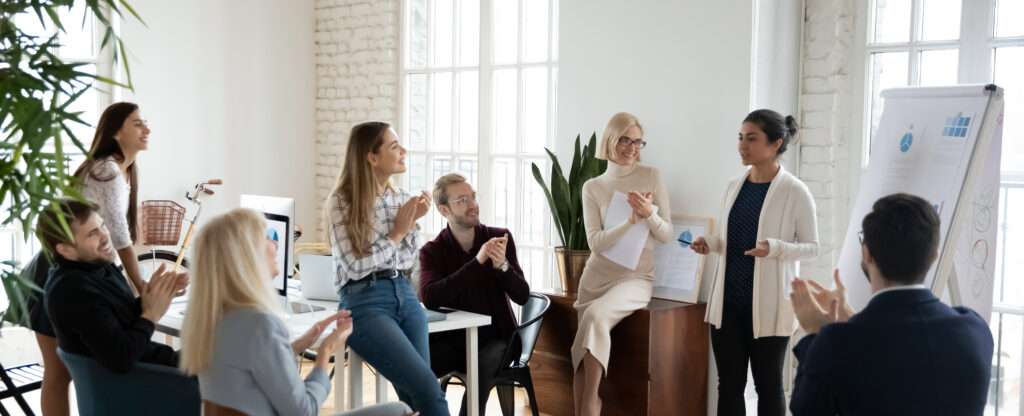 group of people gathered together in front of a presentation board listening to a speaker