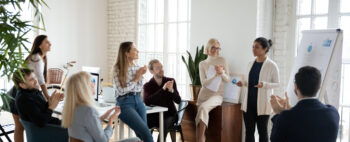 group of people gathered together in front of a presentation board listening to a speaker