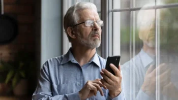Man with cell phone looking out the window