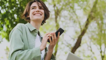 woman holding her cell phone in a park