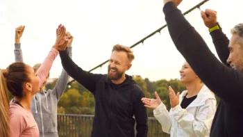 crowd of people cheering, raising their hands in the air.