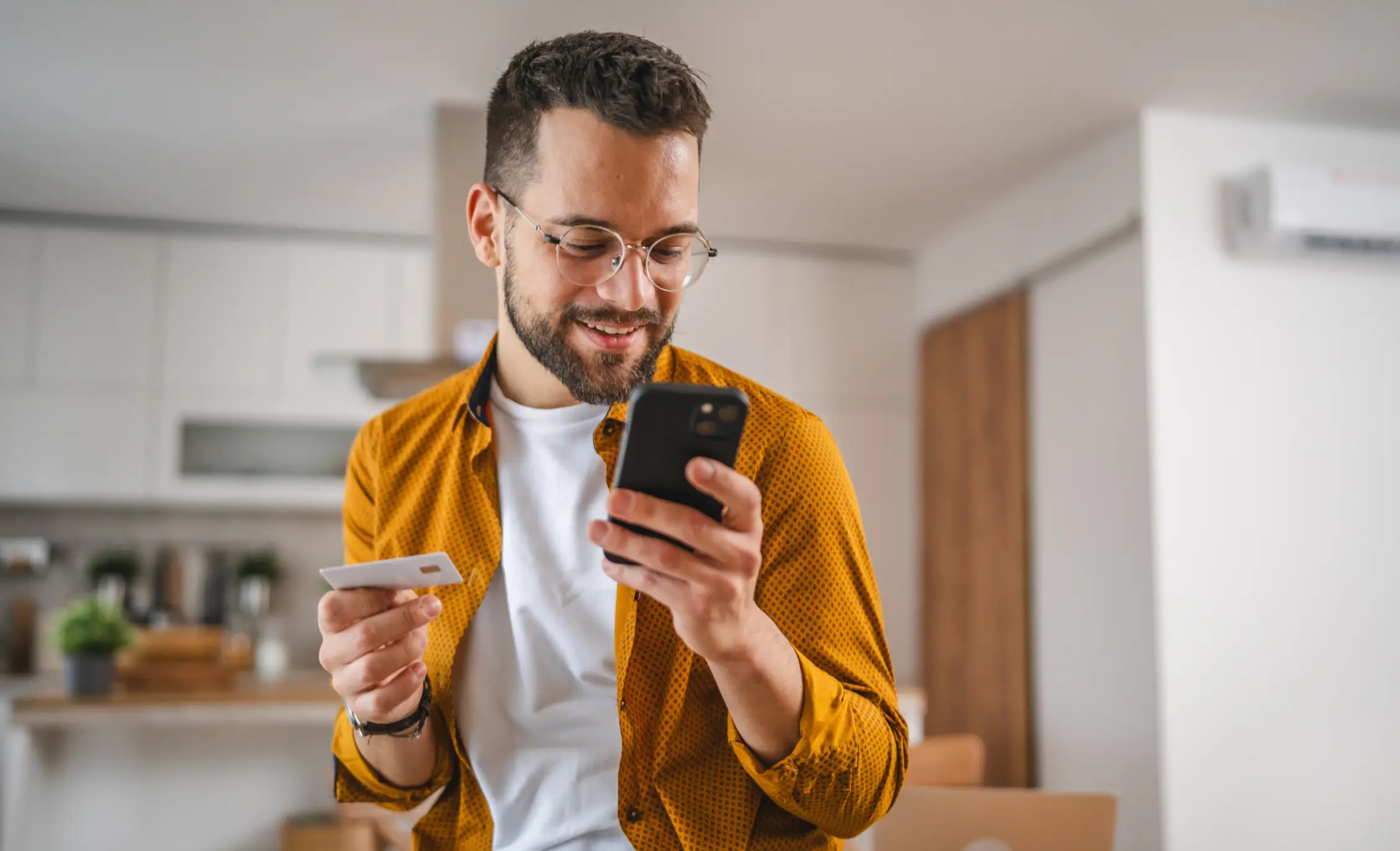 man holding cell phone in one hand and a credit card in the other