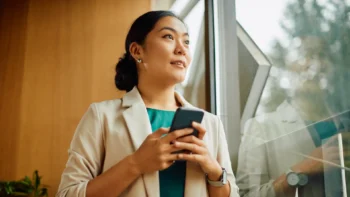 woman looking out the window with a cell phone in her hands