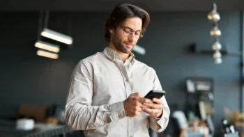 man in an office typing on cell phone