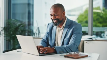 map at his desk on a laptop