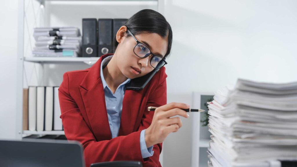 Employee on the phone with a stack of documents