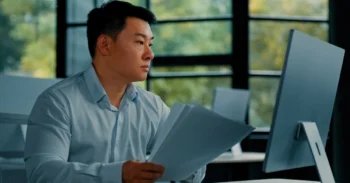 Employee with papers looking at a monitor